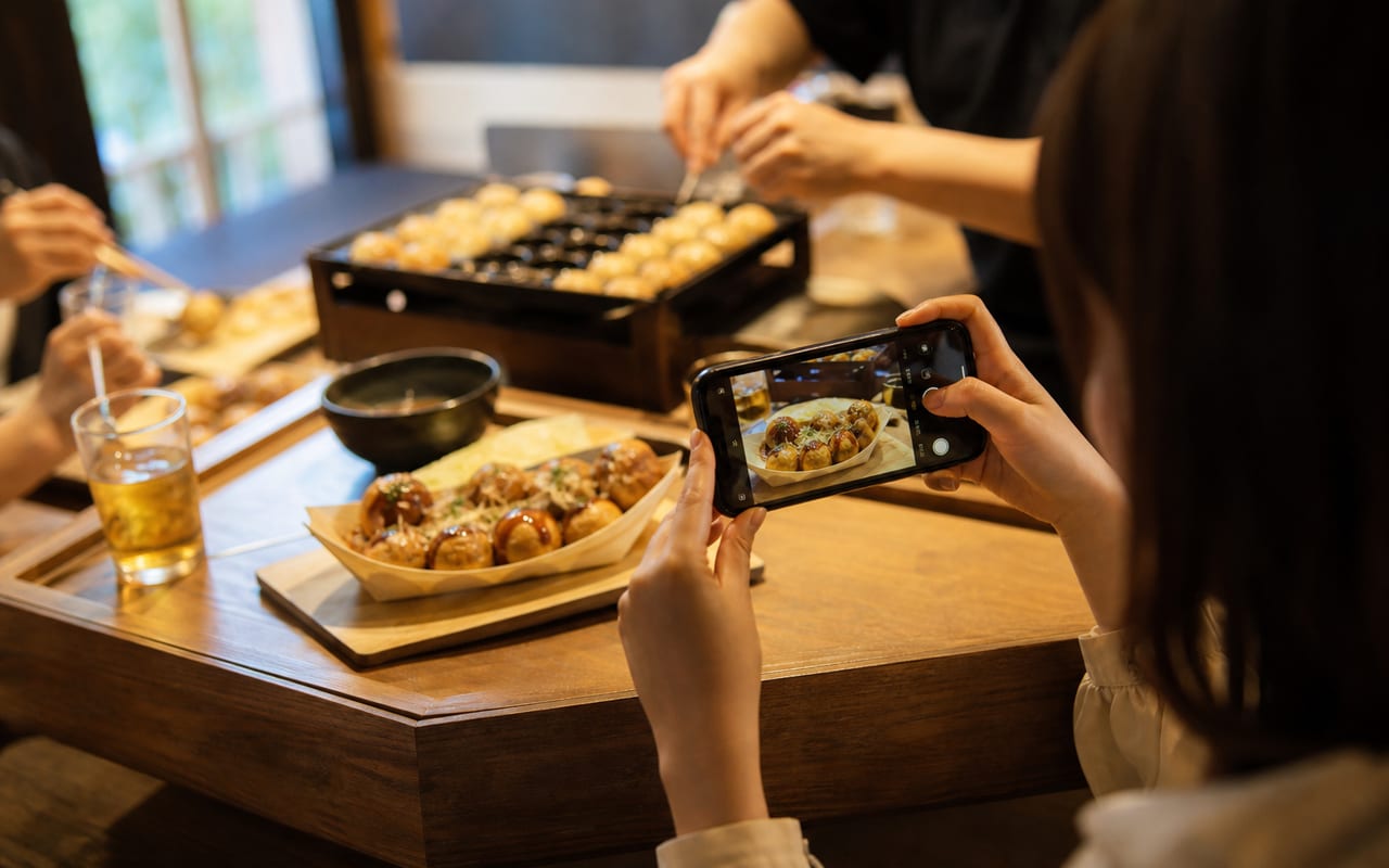 焼きあがったたこ焼きをスマホで撮影するようす